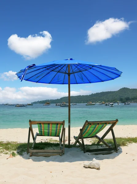 En chaise salonger och mörk blå parasoll — Stockfoto