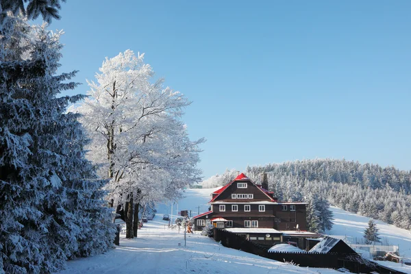 Schneebedeckte Piste und ein gemütliches Skihotel — Stockfoto
