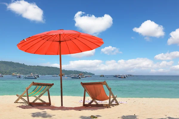 Rode parasol en ligstoelen op het zand — Stockfoto