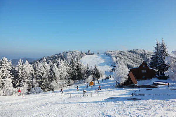 Pista cubierta de nieve, teleférico y muchos esquiadores — Foto de Stock
