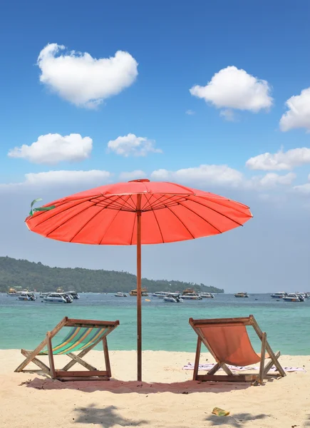 Um guarda-chuva de praia vermelho e salões de chaise — Fotografia de Stock