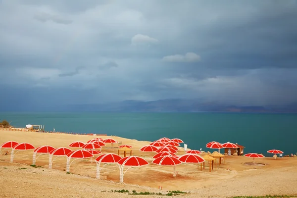 Red umbrellas and green sea — Stockfoto