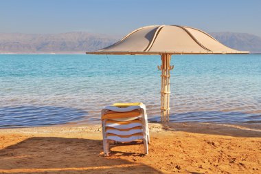 The beach umbrella and a chaise lounge expect tourists clipart