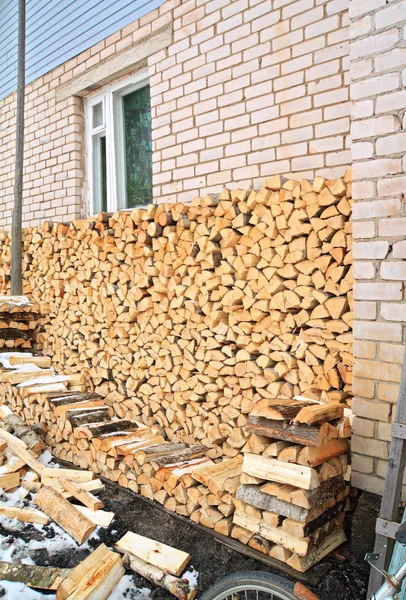 Brandhout in de buurt van de muur van het landelijke gebouw — Stockfoto
