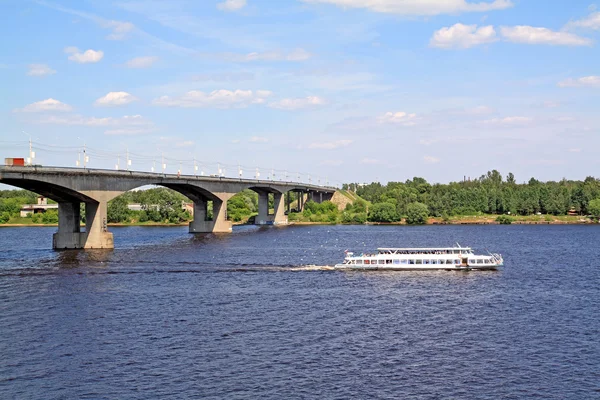 Малий набережний моторний корабель на великій річці біля мосту — стокове фото