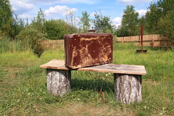 Παλιά βαλίτσα κοντά ξύλινο πάγκο — Φωτογραφία Αρχείου