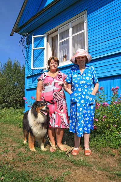 Duas mulheres com cão perto do edifício rural — Fotografia de Stock