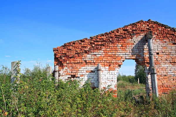 Red brick destroyed building amongst green herb — Stock Photo, Image