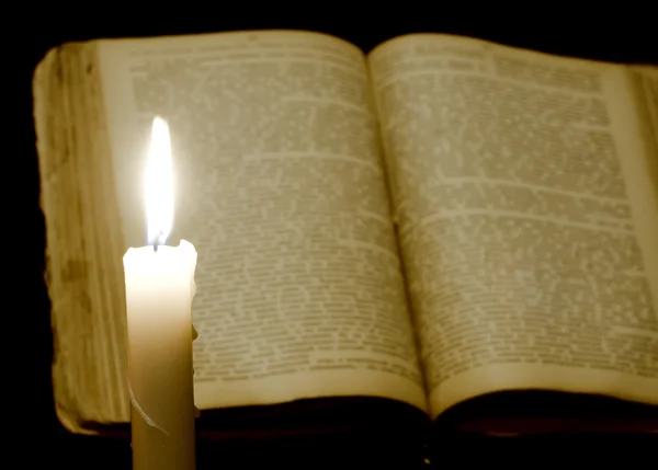 Kerze auf Buch auf schwarz — Stockfoto