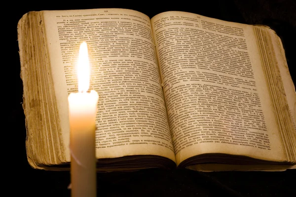 Svíčka na knihu na černém pozadí — Stock fotografie