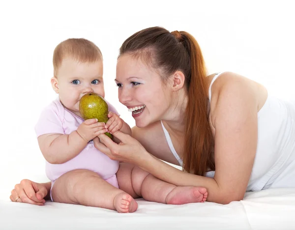 Glückliche Mutter füttert das Baby mit einer Birne. — Stockfoto