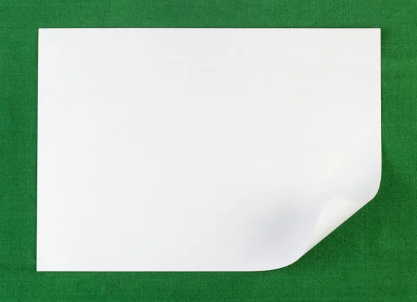 Biała kartka papieru z krawędzi zwinięte na zielonym tle — Zdjęcie stockowe