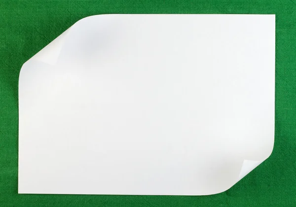 Белый лист бумаги с загнутой кромкой на зеленом фоне — стоковое фото
