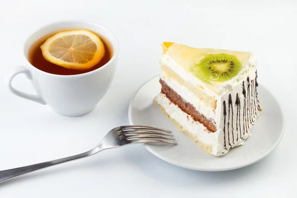 A cup of tea and a piece of tasty creamy cake with fruits — Stock Photo, Image