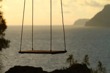 Wooden swing chair near the ocean clipart