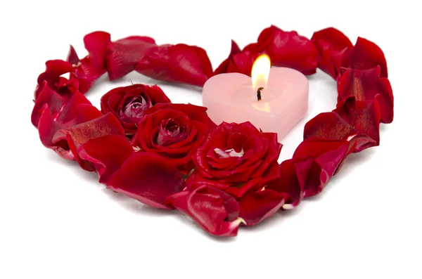 A burning candle in rose petals in heart shape — Stock Photo, Image