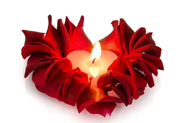 A burning candle in rose petals in heart shape — Stock Photo, Image