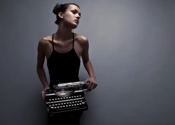 Elegáns nő pózol a régi typewriter. — Stock Fotó