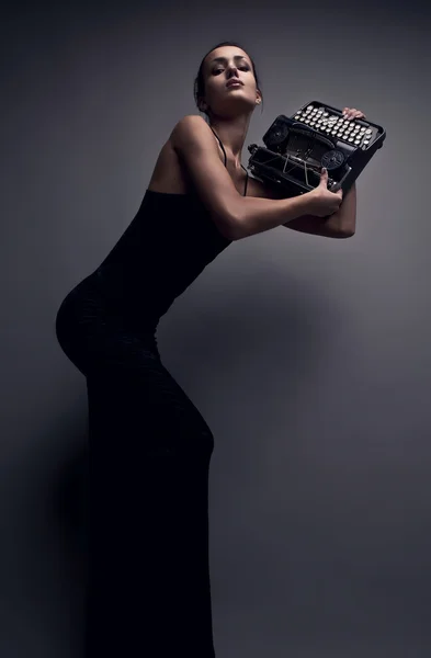Elegáns nő pózol a régi typewriter. — Stock Fotó