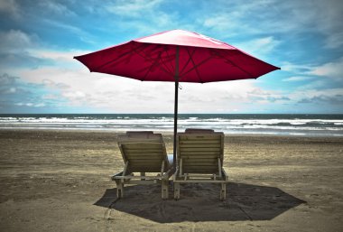 Red beach umbrella and deck chairs on the white sand. Tropical paradise on clipart