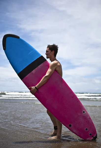 Jovem surfista atraente com uma prancha de surf — Fotografia de Stock