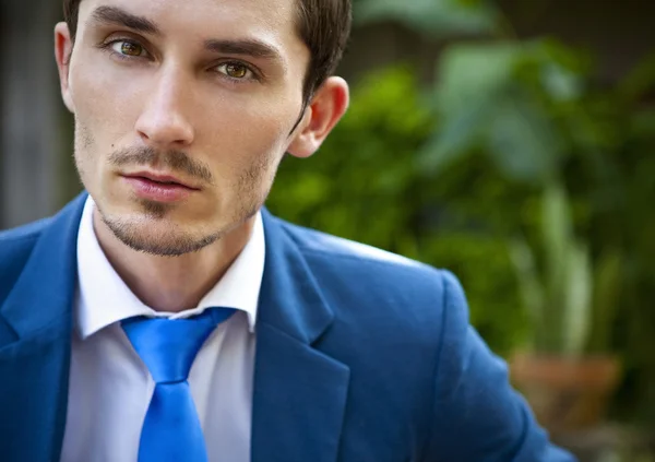 Portret van een goed uitziende mooie jonge man in kostuum buitenshuis. — Stockfoto