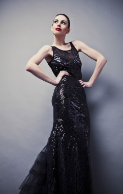 Siyah klasik elbiseli güzel bir kadın stüdyoda poz veriyor..