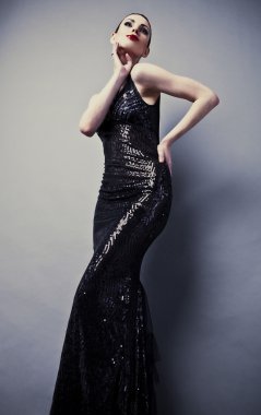 Siyah klasik elbiseli güzel bir kadın stüdyoda poz veriyor..