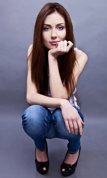 Mladá atraktivní žena sedící na podlaze ateliéru. — Stock fotografie