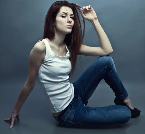 Young attractive woman siting on the studio floor. — Stock Photo, Image