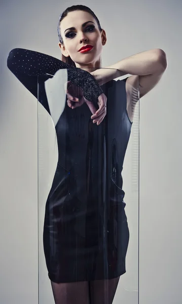 Молодая красивая брюнетка позирует в модном платье возле декоративного стекла . — стоковое фото