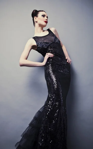 Όμορφη γυναίκα σε μαύρο κλασικό φόρεμα θέτουν σε στούντιο. — Φωτογραφία Αρχείου