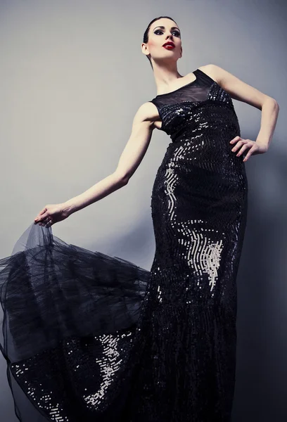 Красива жінка на чорній класичній сукні позує в студії . — стокове фото