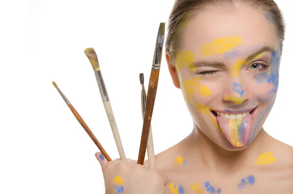 Frau mit Pinsel und Farbe im Gesicht zeigt Zunge — Stockfoto