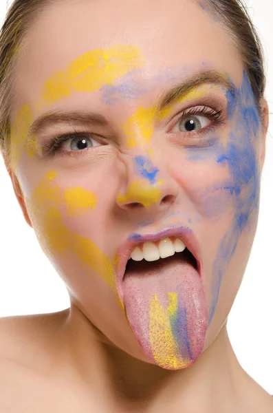 Mulher com tinta no rosto mostra língua — Fotografia de Stock