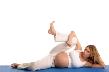 Pregnant woman lying down and practicing yoga clipart