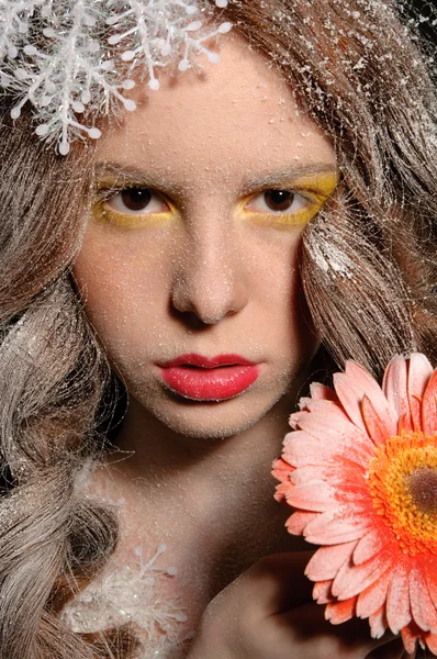 Flicka med blomman i sin hand under fallande snö — Stockfoto