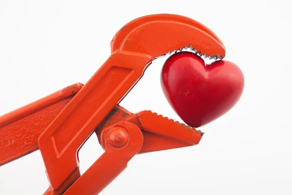 Помаранчевий гайковий ключ, що натискає червоне серце — стокове фото