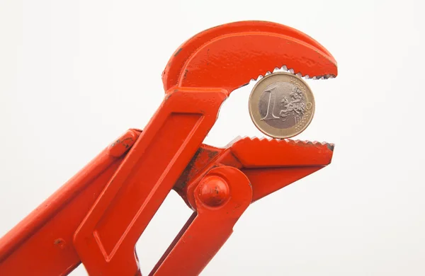 Orange wrench pressing a euro coin — Stock Photo, Image