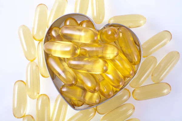Vitamin capsules arranged in the shape of a heart — Stock Photo, Image