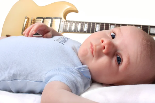 Малыш лежит с гитарой — стоковое фото