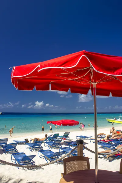 Červená slunečníky a tyrkysovými vodami Karibiku — Stock fotografie