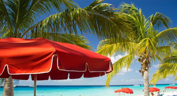 रेड बीच छत्री आणि कॅरिबियनचे टर्किझ पाणी — स्टॉक फोटो, इमेज