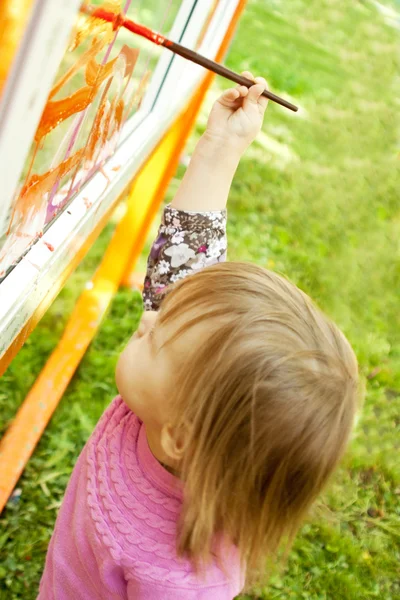 Cute little girl is drawing on the glass — Stock Photo, Image