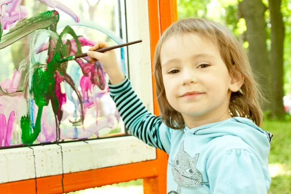 Linda niña está dibujando en el vidrio — Foto de Stock