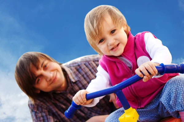 Father and daughter are playing with tricycle — Stock Photo, Image