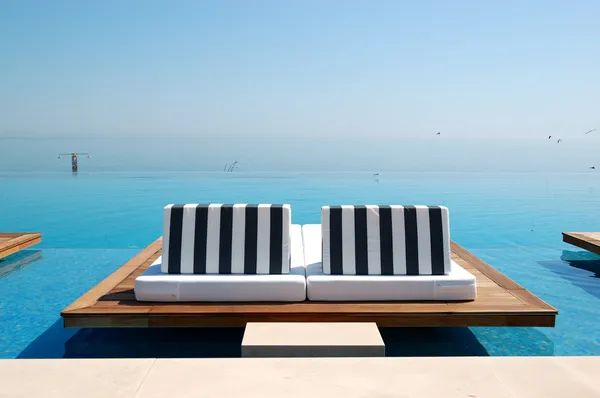 Infinity swimming pool by beach at the modern luxury hotel, Pier Stock Photo