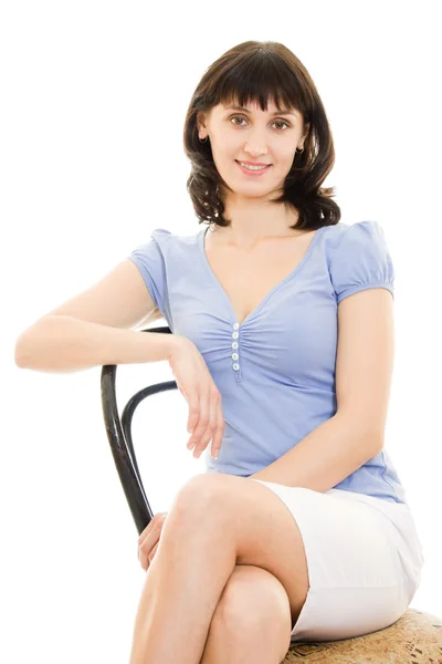 Una mujer con camisa azul y falda blanca sentada en una silla sobre un respaldo blanco —  Fotos de Stock
