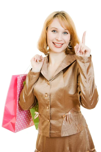 Uma bela mulher em um terno de ouro com compras aponta um dedo para cima em um — Fotografia de Stock