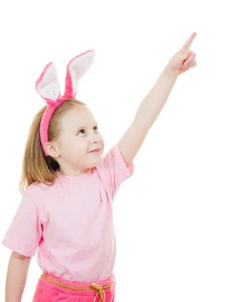 The little girl with pink ears bunny points to the top on white background. — Stock Photo, Image